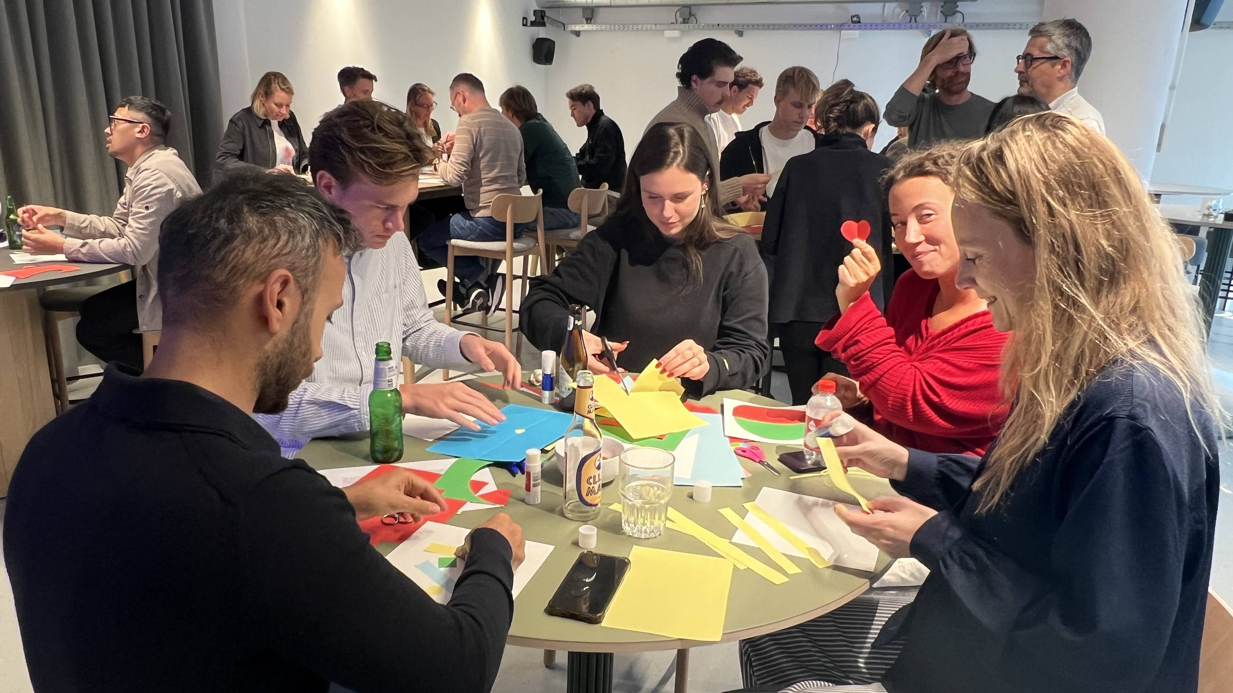 A group of people working with colored paper at a table.